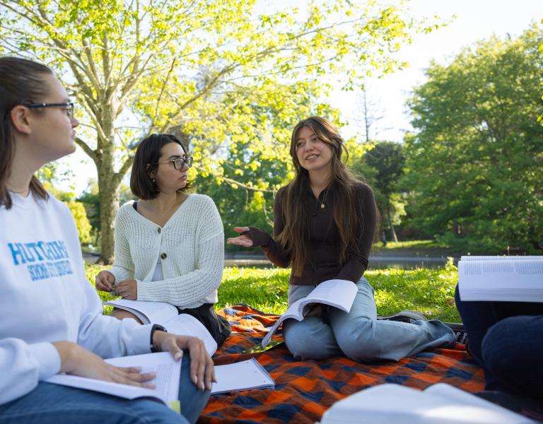Students sitting in a circle reading outside